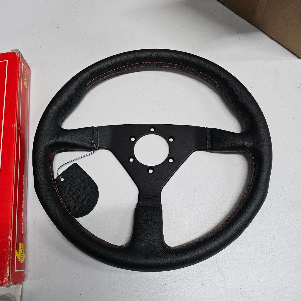 Close‑up of MOMO Montecarlo leather wheel with red stitching and black spokes