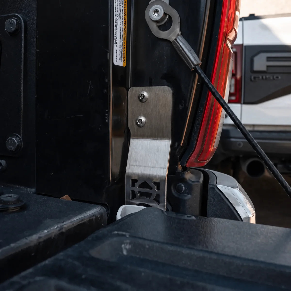 CALI RAISED two-bolt tailgate protector installed at passenger-side Tacoma hinge