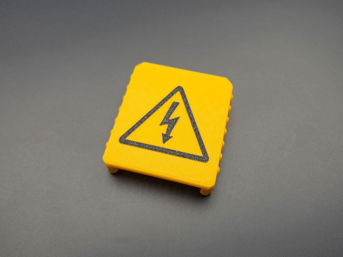 Angled view of 3D-printed yellow M18 battery terminal cover