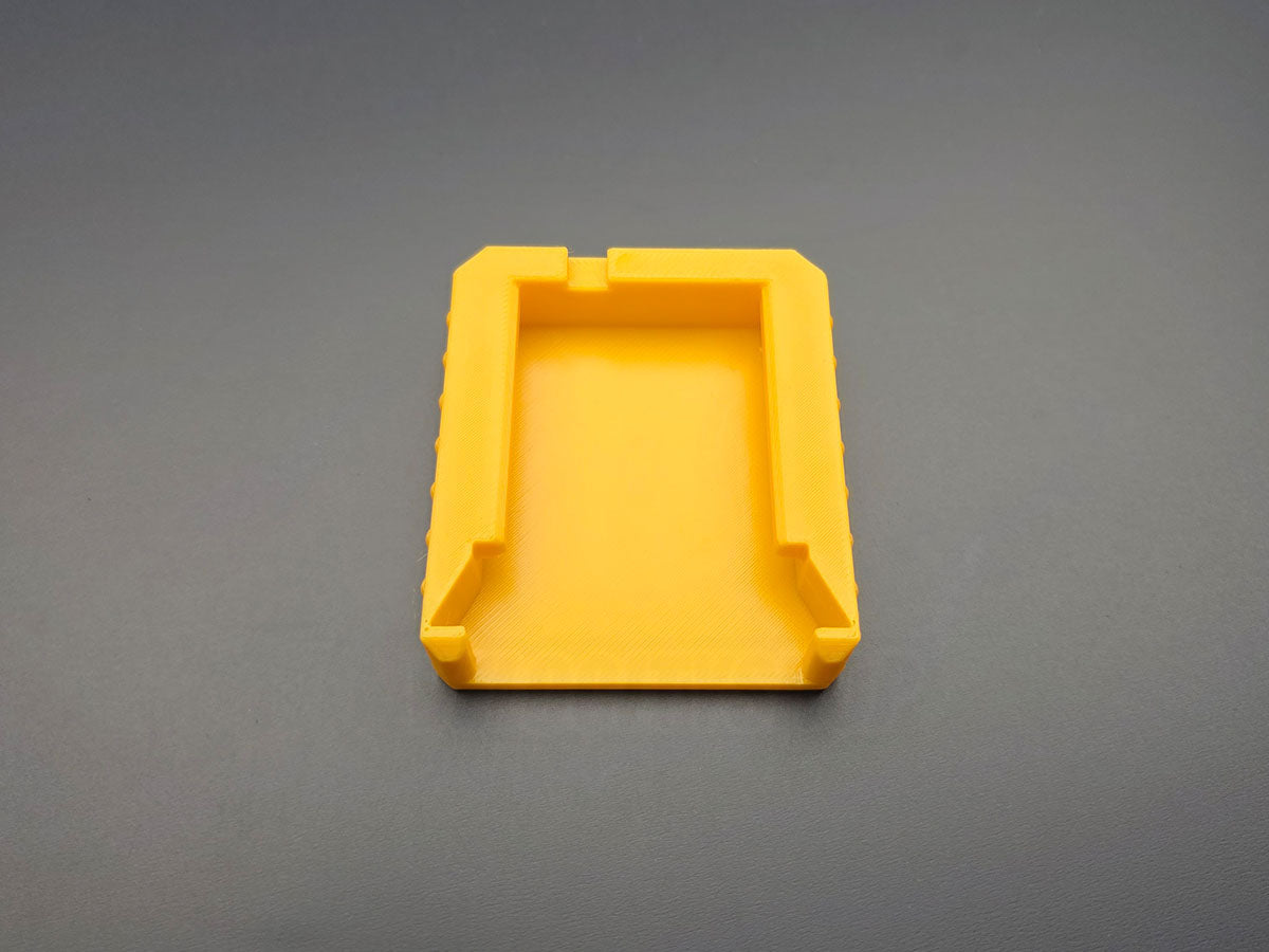 Underside of yellow M18 battery terminal cover showing slide-on mounting rails
