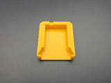 Underside of yellow M18 battery terminal cover showing slide-on mounting rails