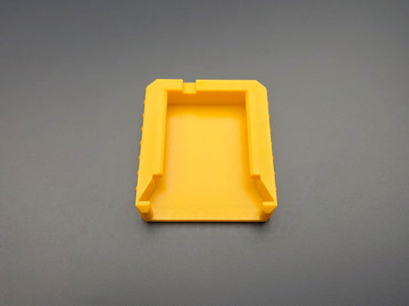 Underside of yellow M18 battery terminal cover showing slide-on mounting rails