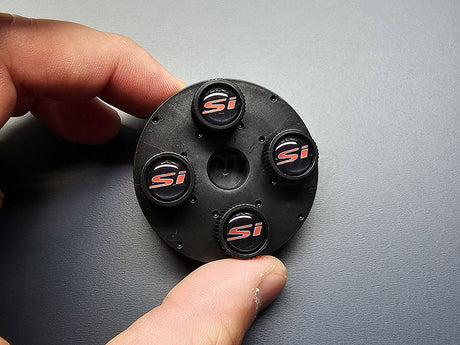 Close-up of OEM Honda Civic Si black valve stem caps with red Si logo 08W48-PL4-100B