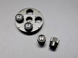 Close-up of OEM Honda black valve stem caps with silver H logo 08W48-PL4-100A