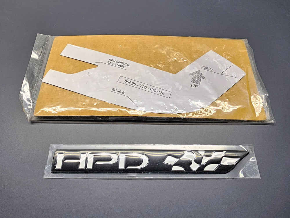 Genuine Honda HPD chrome emblem with installation template.