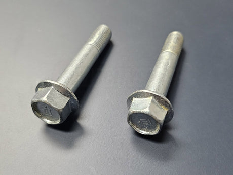 Two OEM Honda rear lower shock bolts laid flat on table – genuine factory hardware for Acura RSX DC5 2002–2006