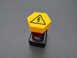 Yellow M12-compatible battery terminal cover with black electrical-warning graphic
