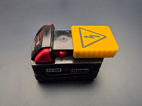 Yellow terminal cover sliding onto a Milwaukee M18 battery interface
